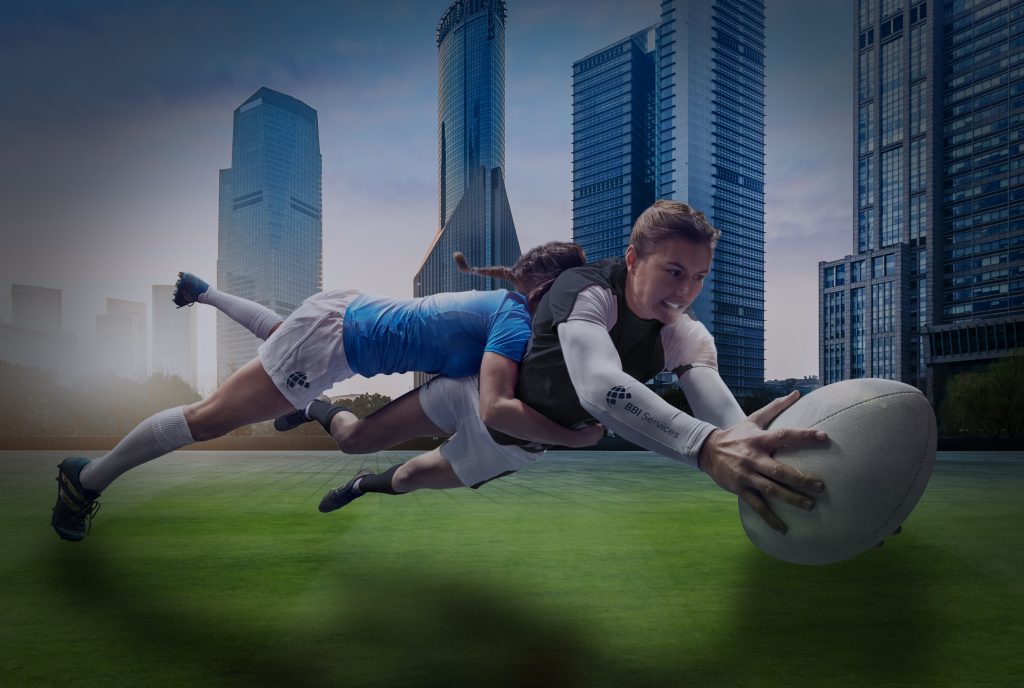 Rugby girls tackling each other on a backdrop of the city