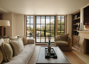 Neutral living room with a cream sofa, wooden coffee table and black steel-framed glazed doors overlooking the garden.